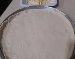 Step <p>Forramos una molde de pizza hasta cubrirla incluso los bordes.</p> illustration